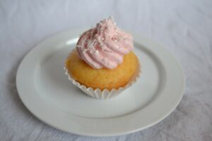 Ananas-Kokos-Cupcake mit Topping auf Porzellanteller